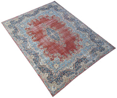 A vintage Persian Kerman rug featuring a central medallion and intricate floral patterns in red.