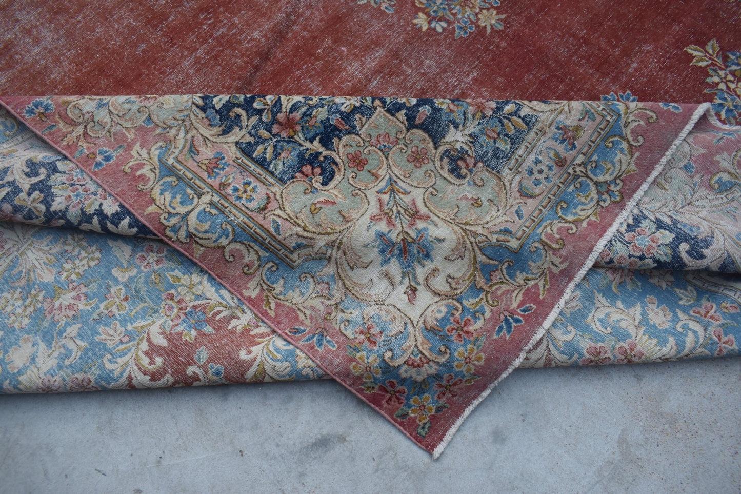 A vintage Persian Kerman rug featuring an intricate floral medallion design in red and blue tones.