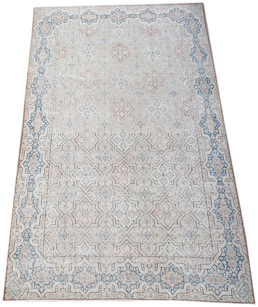 A vintage Persian Kerman rug featuring a light field with intricate floral patterns and blue borders.