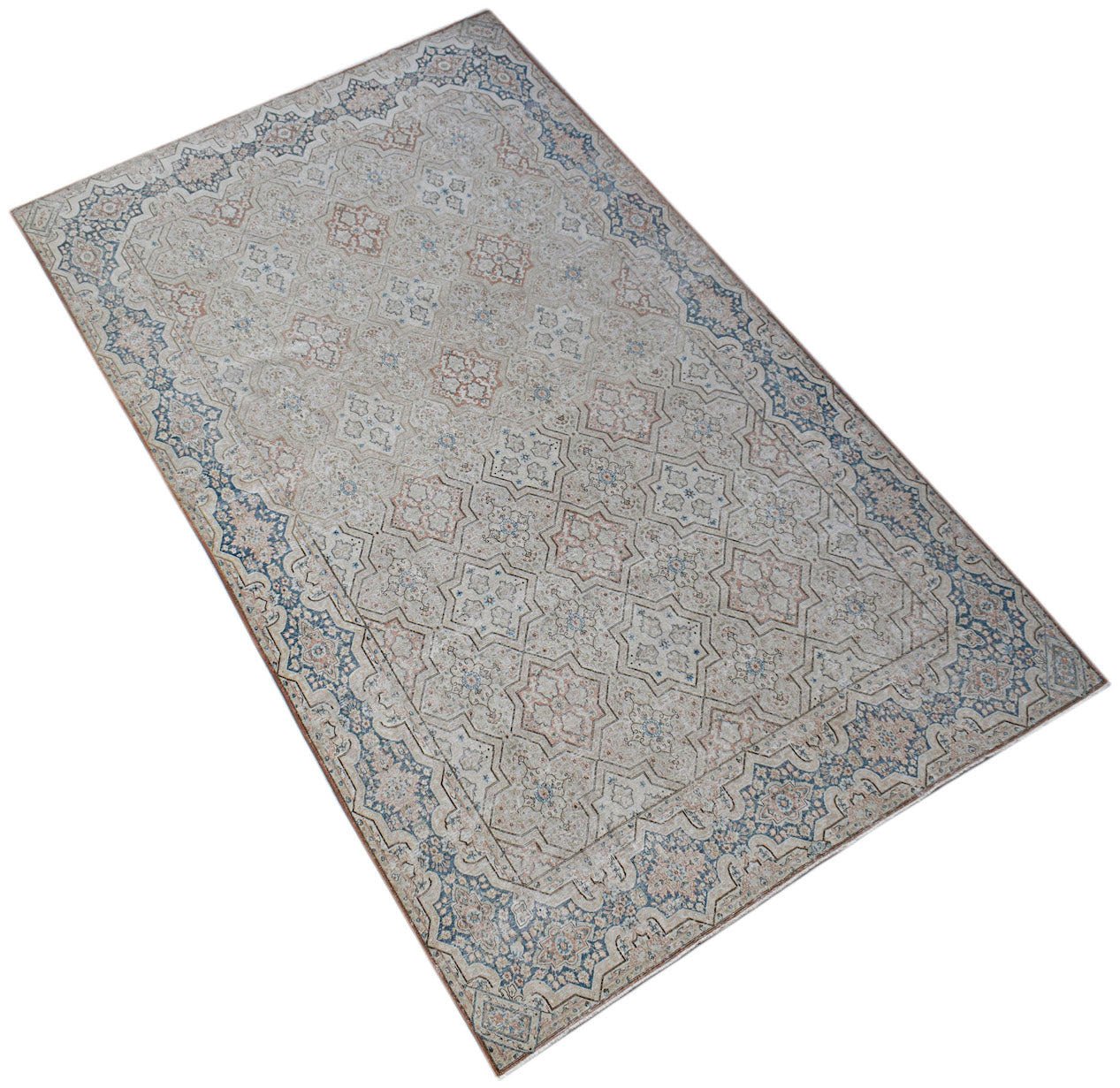 A vintage Persian Kerman rug featuring a soft, intricate floral pattern in blue and beige tones.