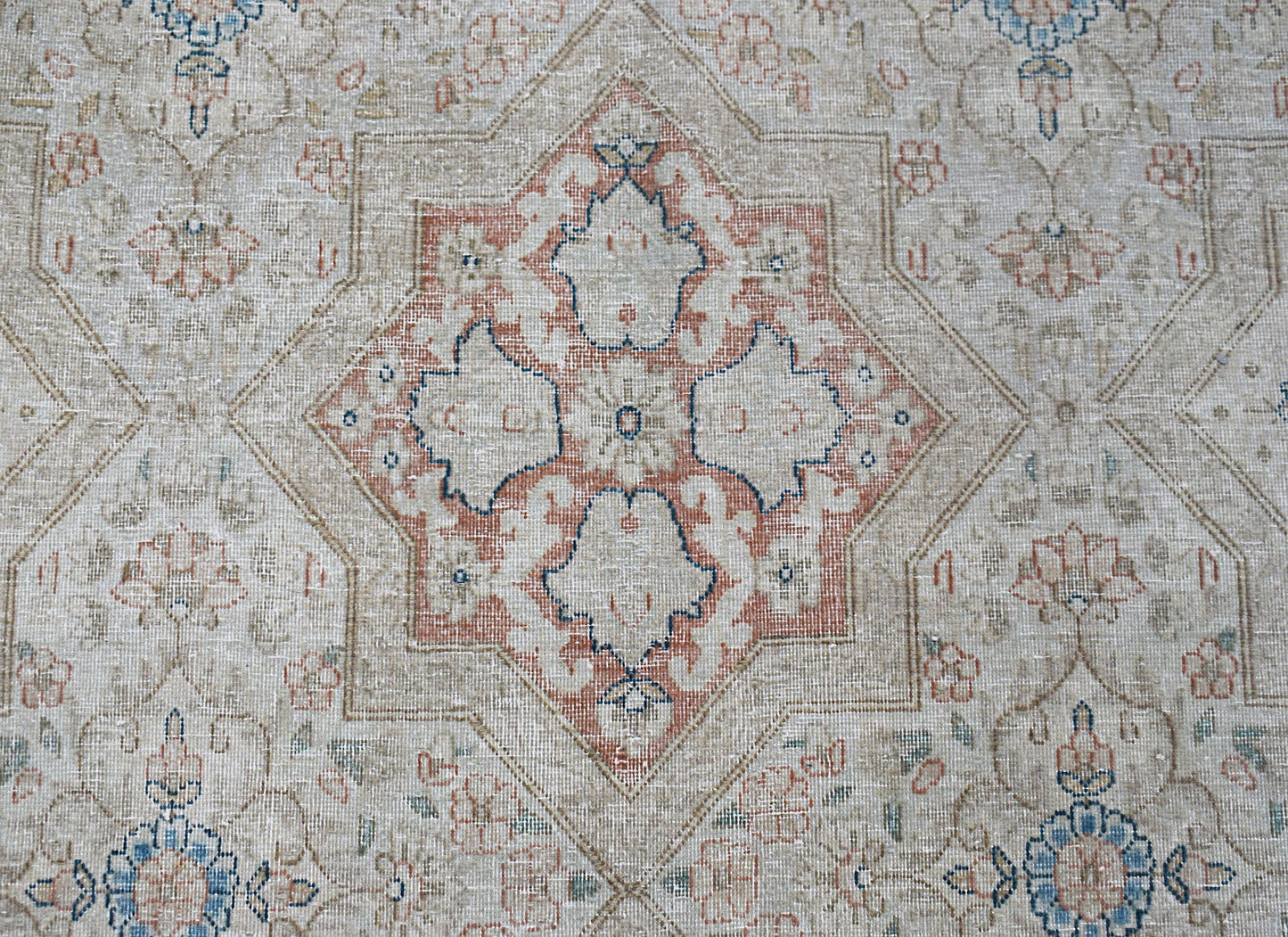 A vintage Persian Kerman rug featuring a central floral medallion in soft blue and terracotta tones.