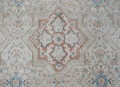 A vintage Persian Kerman rug featuring a central floral medallion in soft blue and terracotta tones.