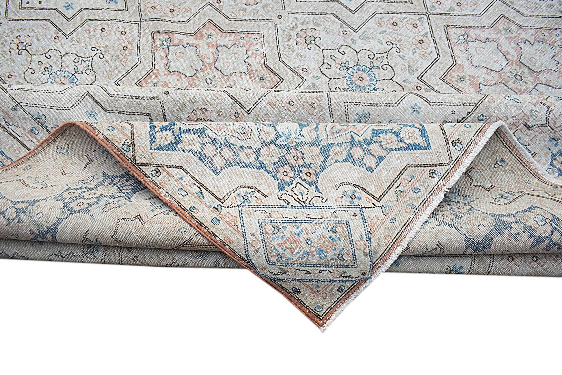 A vintage Persian Kerman rug featuring a geometric star pattern in soft blue and peach tones.
