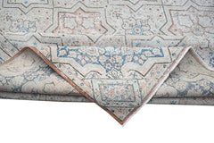 A vintage Persian Kerman rug featuring a geometric star pattern in soft blue and peach tones.