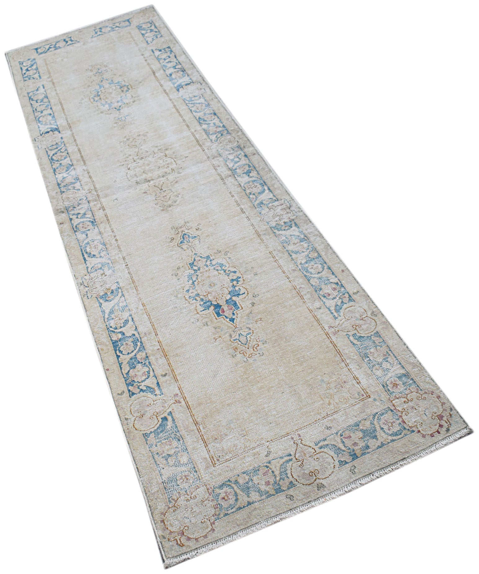 A vintage Persian Kerman runner featuring a central medallion and floral border in blue and beige.