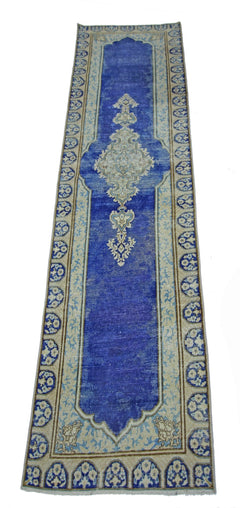 A vintage Persian Kerman runner featuring a central medallion on a blue field with floral borders.