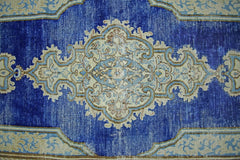 A vintage Persian Kerman runner featuring an intricate central medallion on a deep blue field.