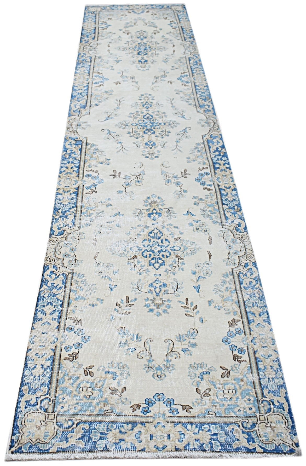 A vintage Persian Kerman runner featuring a blue and cream floral medallion pattern.
