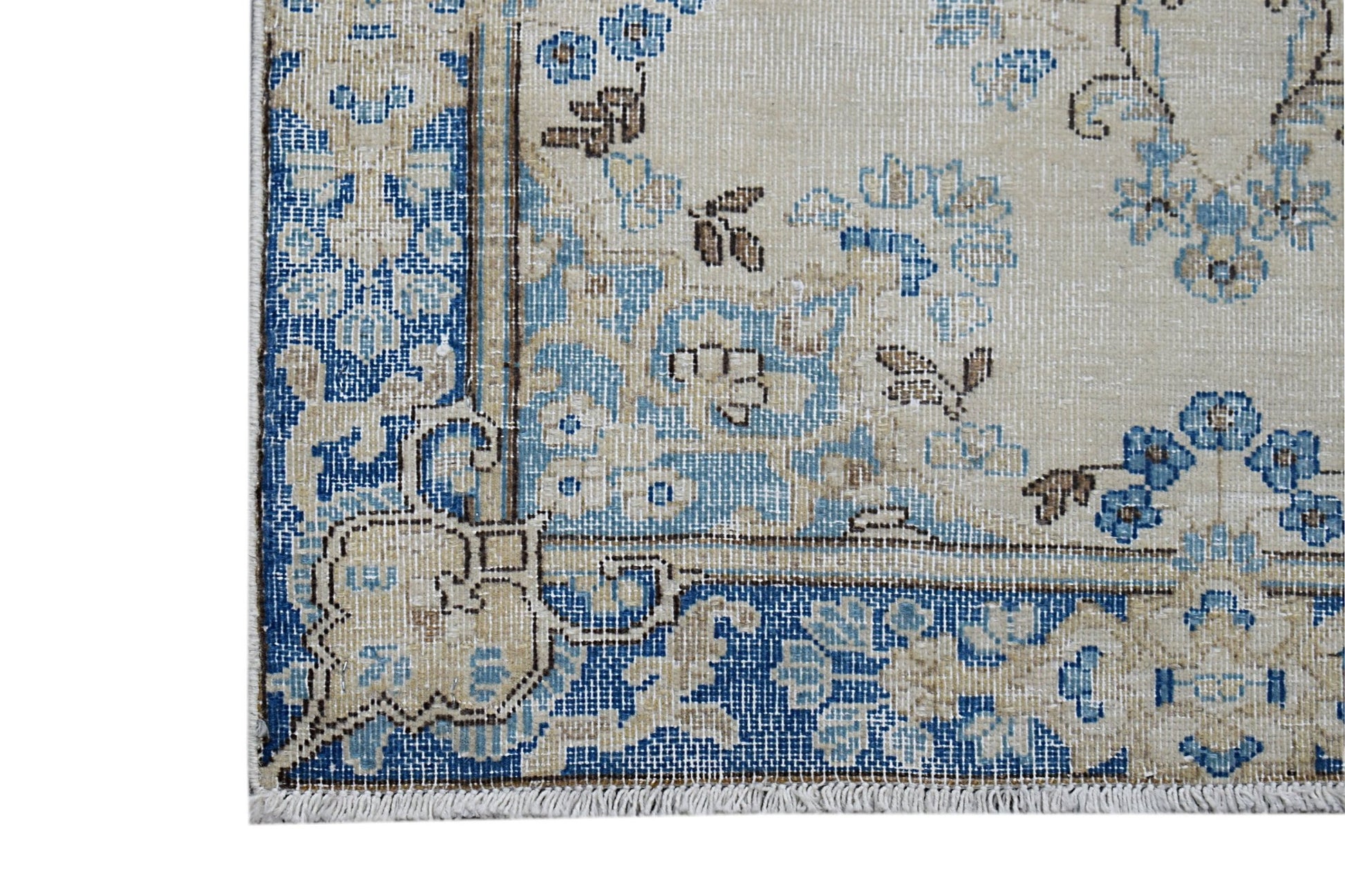 A corner detail of a vintage Persian Kerman runner featuring intricate blue and beige floral motifs.