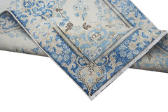 A vintage Persian Kerman runner featuring a blue and cream floral pattern with a folded corner.