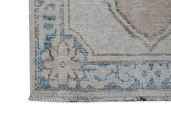 A close-up of a vintage Persian Kerman runner featuring a blue and beige floral medallion pattern.