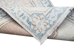 A vintage Persian Kerman runner featuring a blue and beige floral medallion pattern.