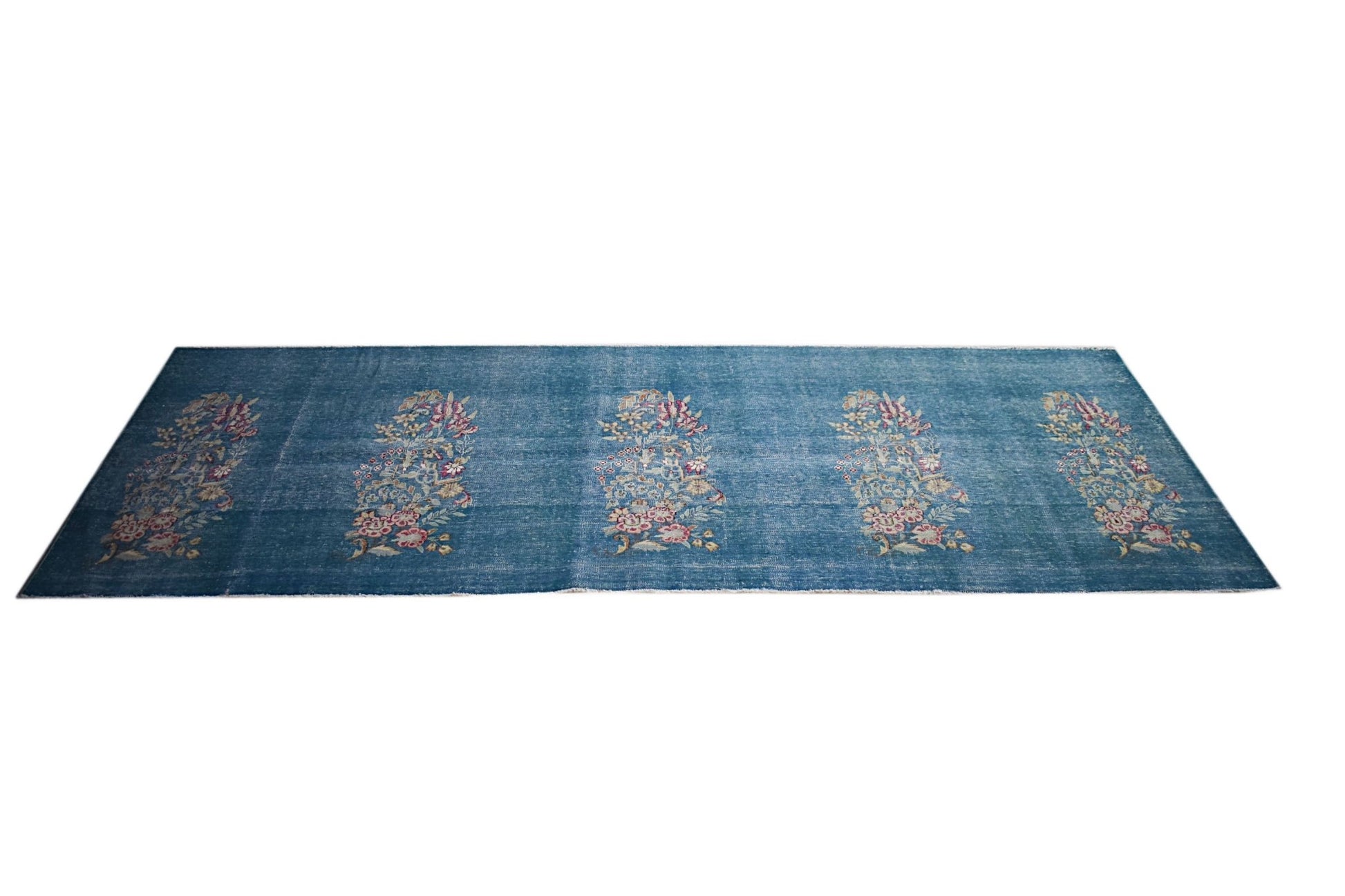 A vintage Persian Kerman runner featuring five floral bouquet motifs on a blue field.