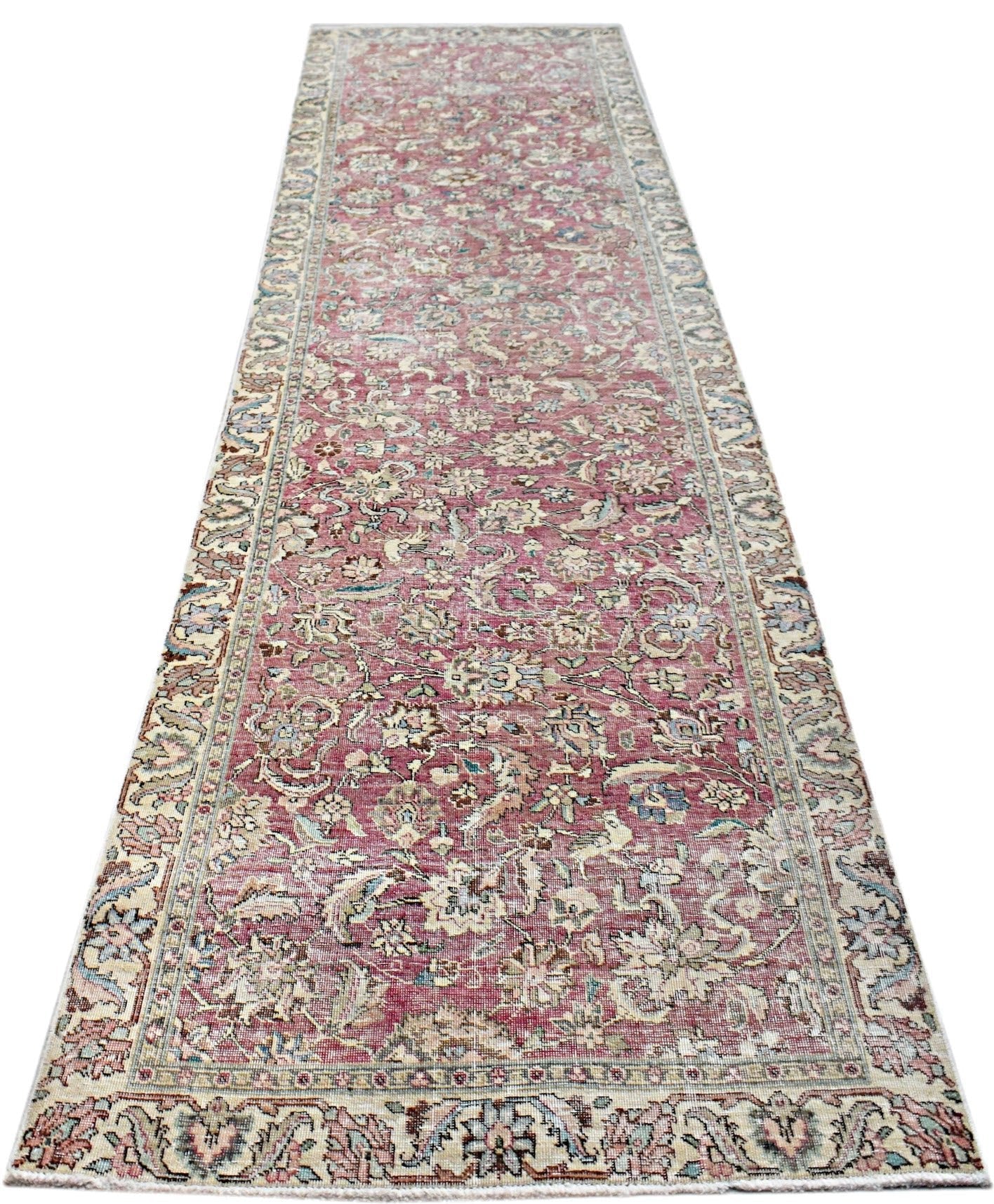 A vintage Persian Kerman runner featuring an intricate floral pattern in shades of pink and blue.