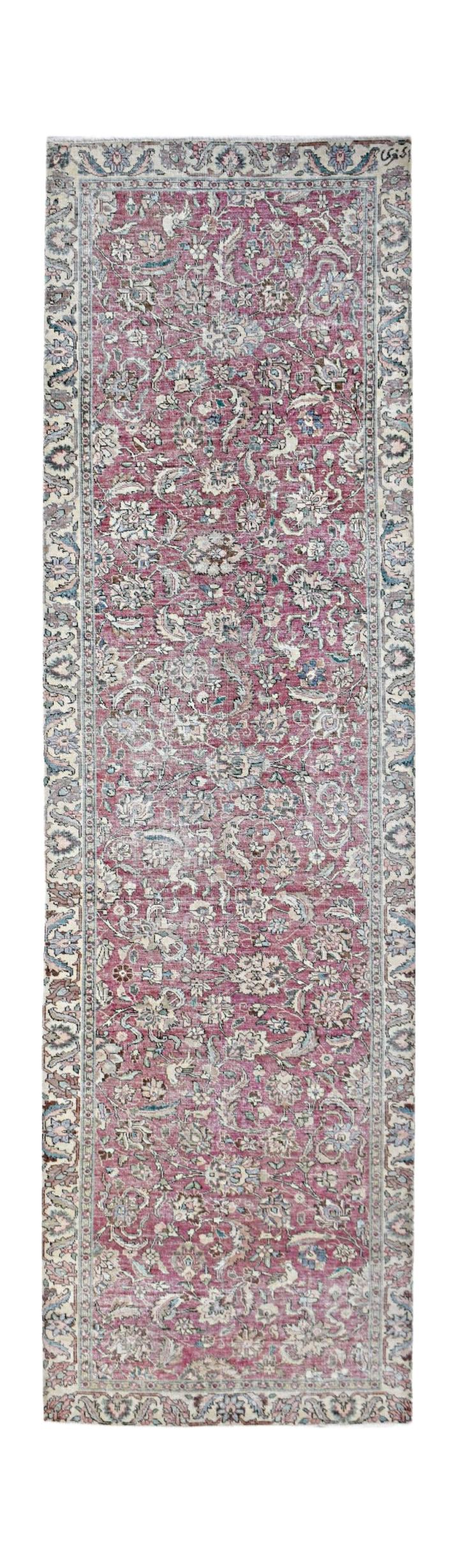 A vintage Persian Kerman runner featuring an intricate floral pattern in shades of pink and blue.