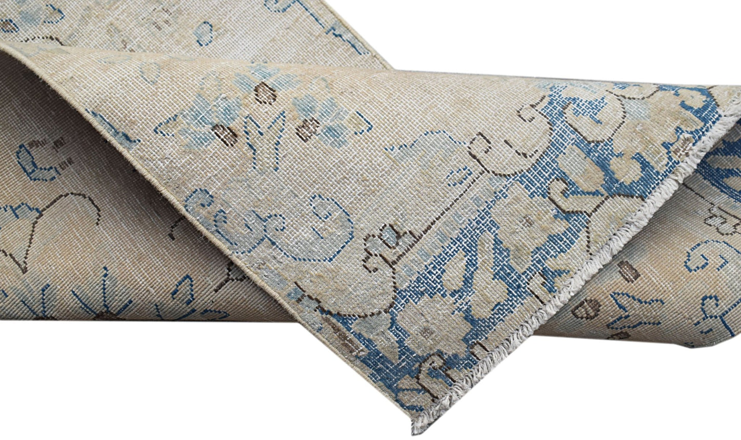 A vintage Persian Kerman runner featuring a beige field with intricate blue floral patterns.
