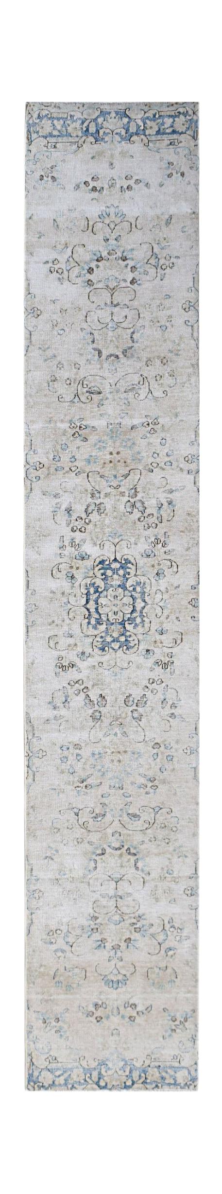 A vintage Persian Kerman runner rug featuring a central blue floral medallion on a beige field.