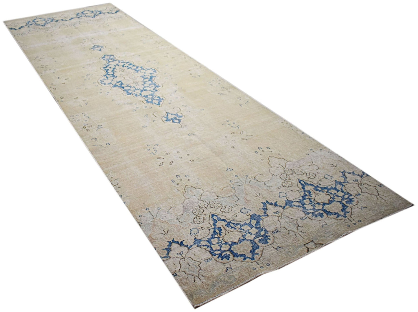 A vintage Persian Kerman runner featuring a blue floral medallion on a light beige background.