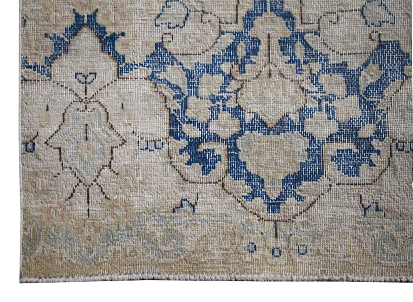 A vintage Persian Kerman runner featuring a blue floral medallion on a neutral beige background.