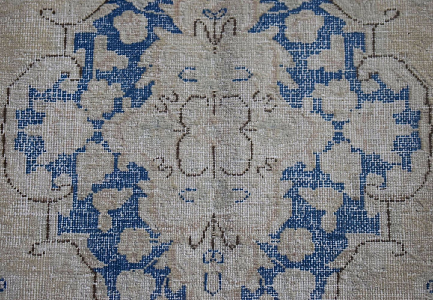 A vintage Persian Kerman runner featuring a central floral medallion in blue on a beige field.