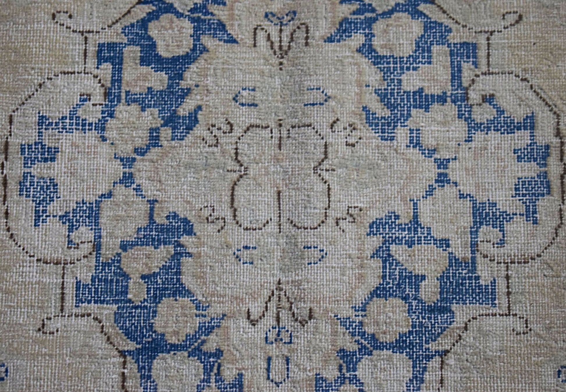 A vintage Persian Kerman runner featuring a central floral medallion in blue on a beige field.