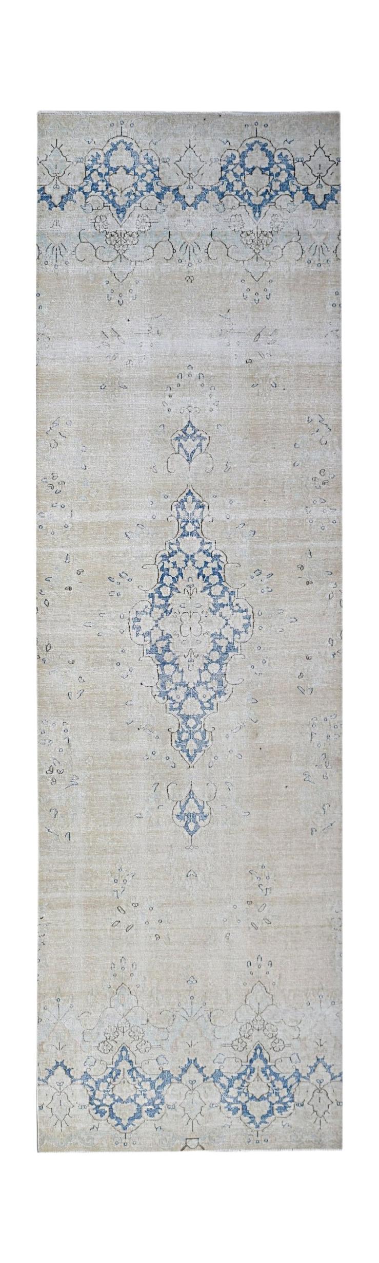 A vintage Persian Kerman runner featuring a blue floral medallion on a light beige background.