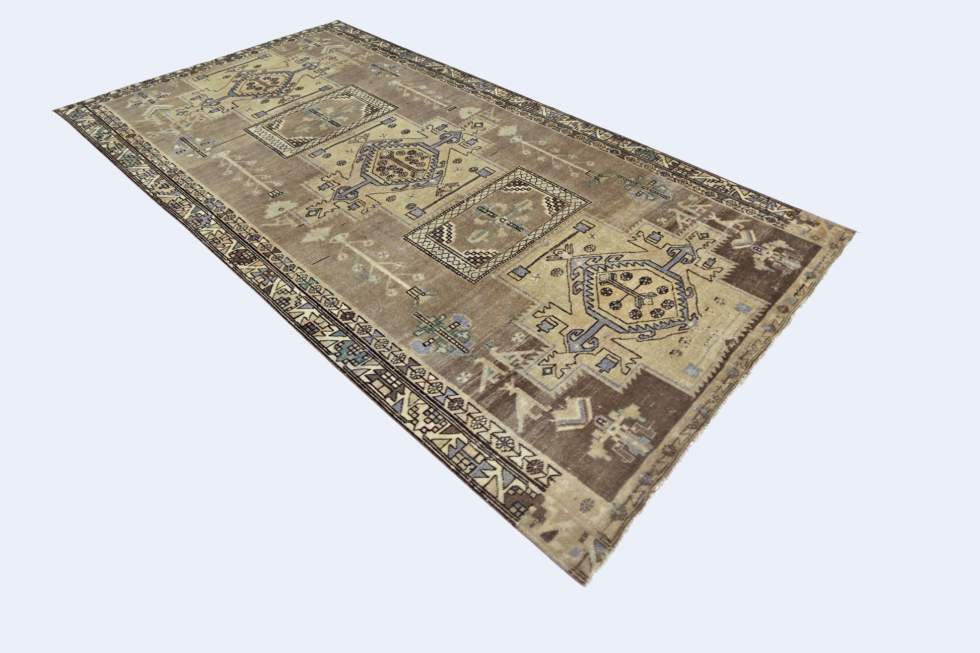 A vintage Persian rug featuring geometric patterns in muted brown, blue, and cream tones.