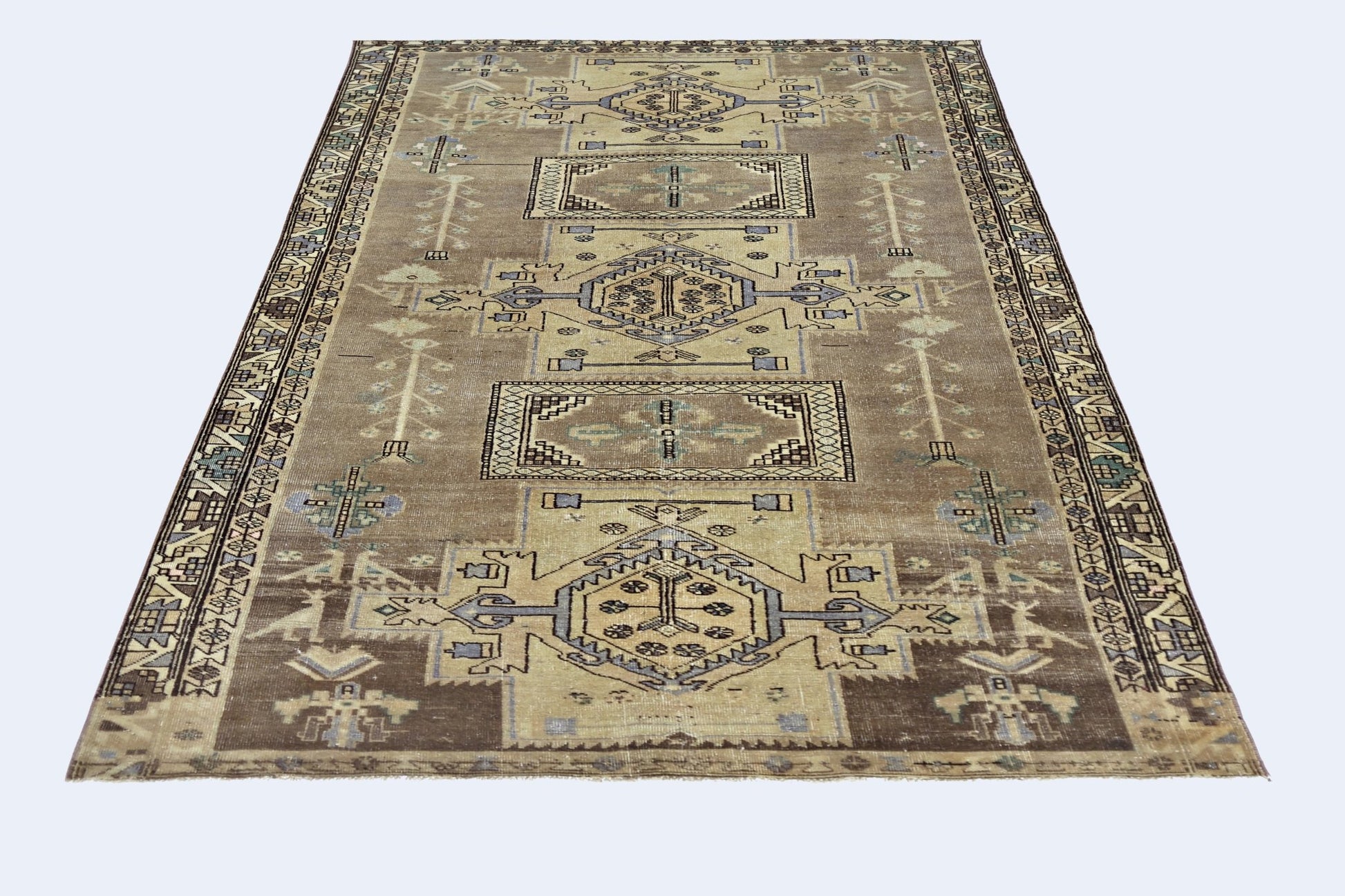 A vintage Persian rug featuring geometric patterns in shades of brown, blue, and cream.