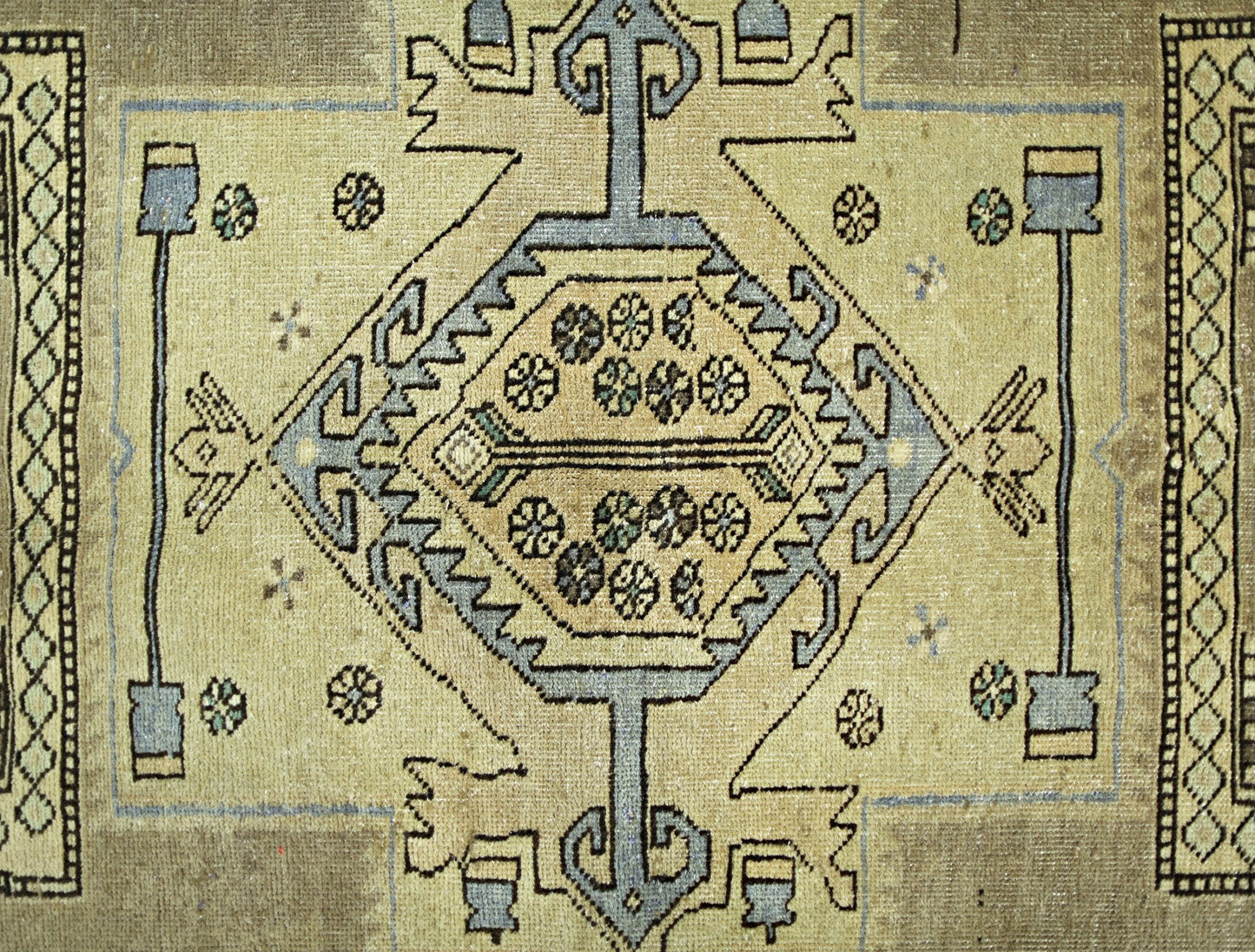 A vintage Persian rug featuring a central geometric medallion with floral motifs on a tan field.