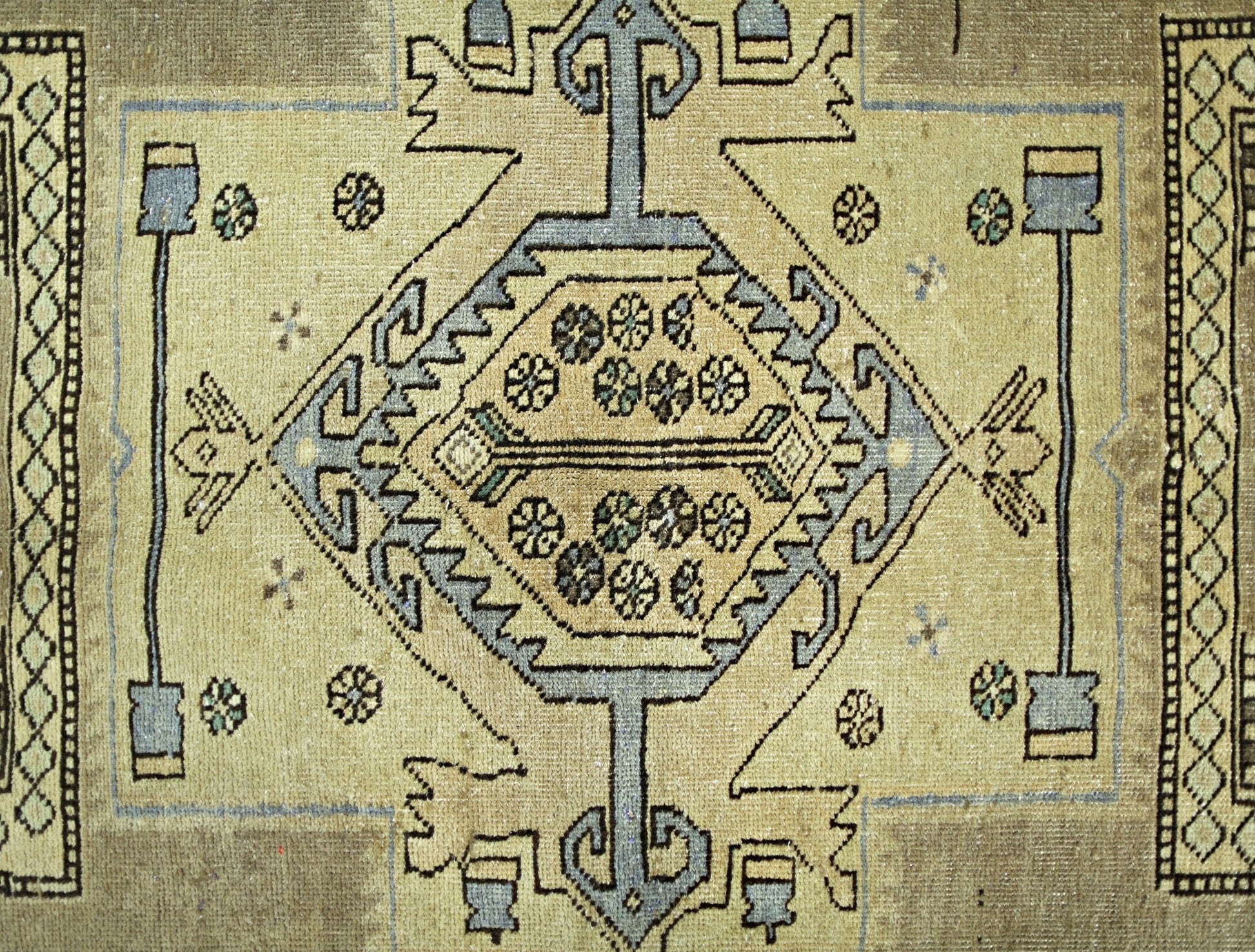 A vintage Persian rug featuring a central geometric medallion with floral motifs on a tan field.