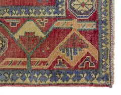 A close-up of a vintage handmade Persian rug featuring geometric patterns in red, blue, and tan.