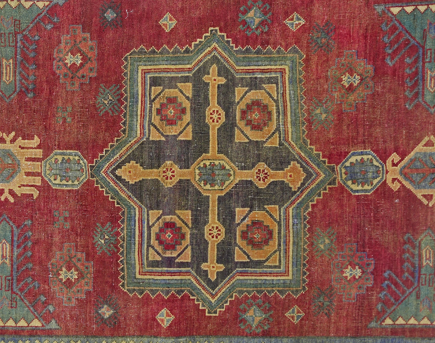 A vintage Persian rug featuring a central geometric medallion in red, blue, and gold tones.