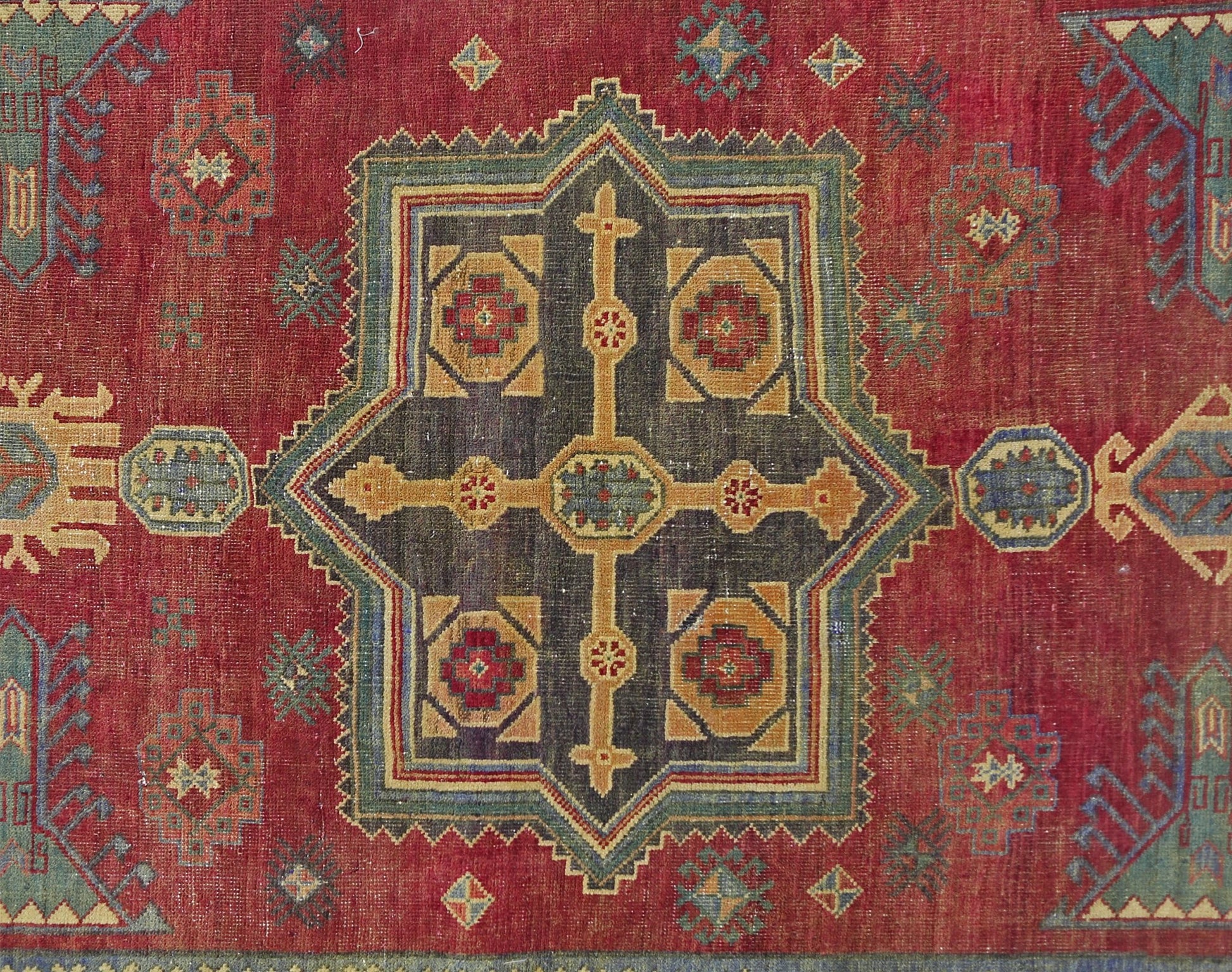 A vintage Persian rug featuring a central geometric medallion in red, blue, and gold tones.