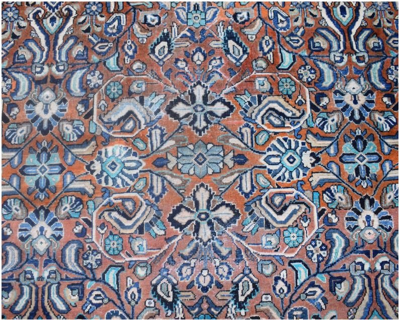 A vintage Persian Lori rug featuring a repeating geometric floral pattern in blue and orange tones.