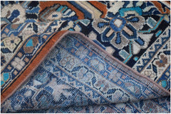 A corner of a vintage Persian Lori rug is folded back to show its intricate blue wool weave.