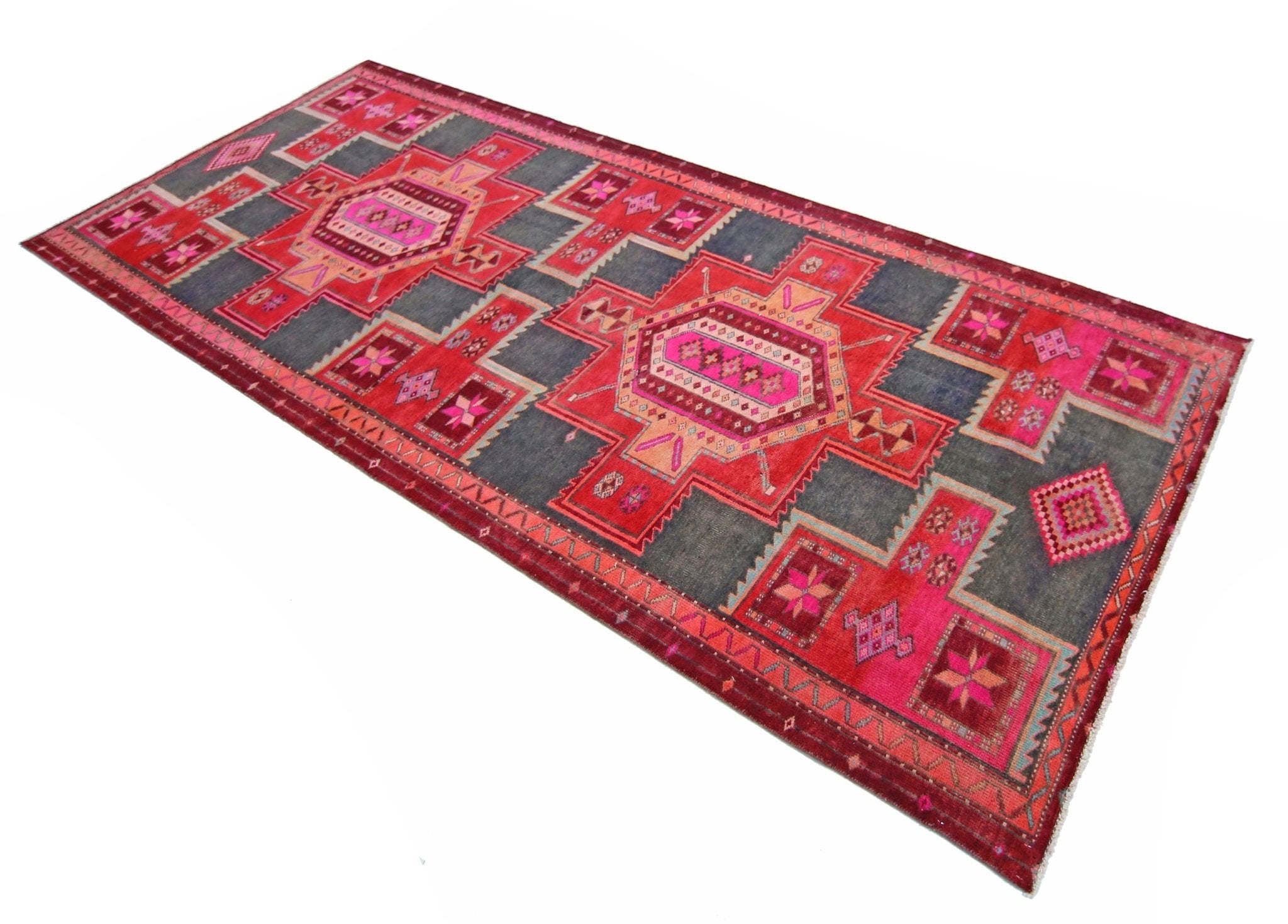 A handmade vintage Persian runner rug featuring geometric medallions in shades of red and grey.