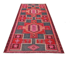 A handmade vintage Persian runner rug featuring geometric patterns in red, pink, and dark grey.