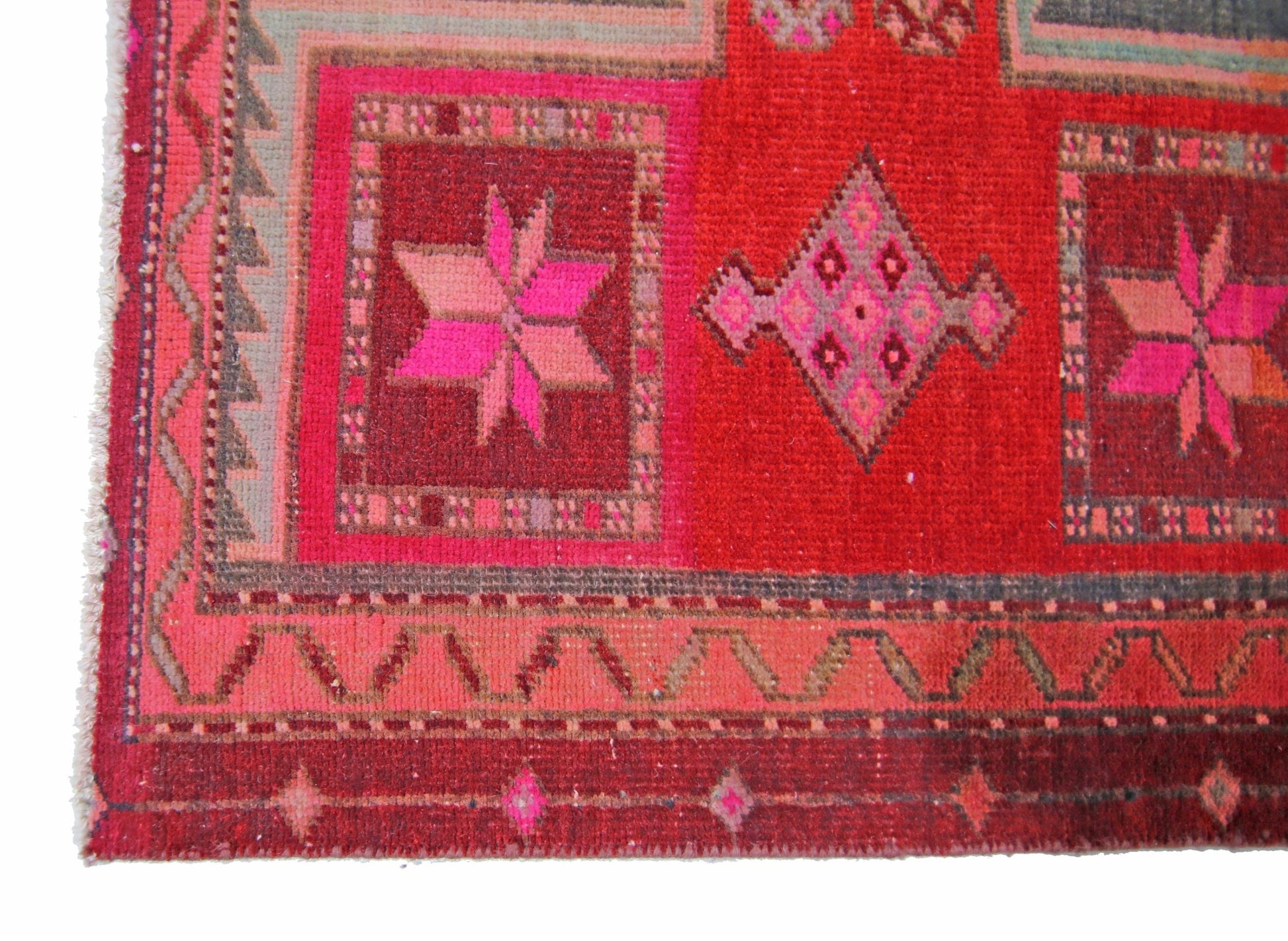 A vintage handmade Persian rug featuring geometric star and diamond patterns in shades of red.