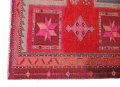 A vintage handmade Persian rug featuring geometric star and diamond patterns in shades of red.