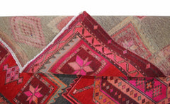 A vintage Persian rug with geometric patterns in shades of red, pink, and grey.
