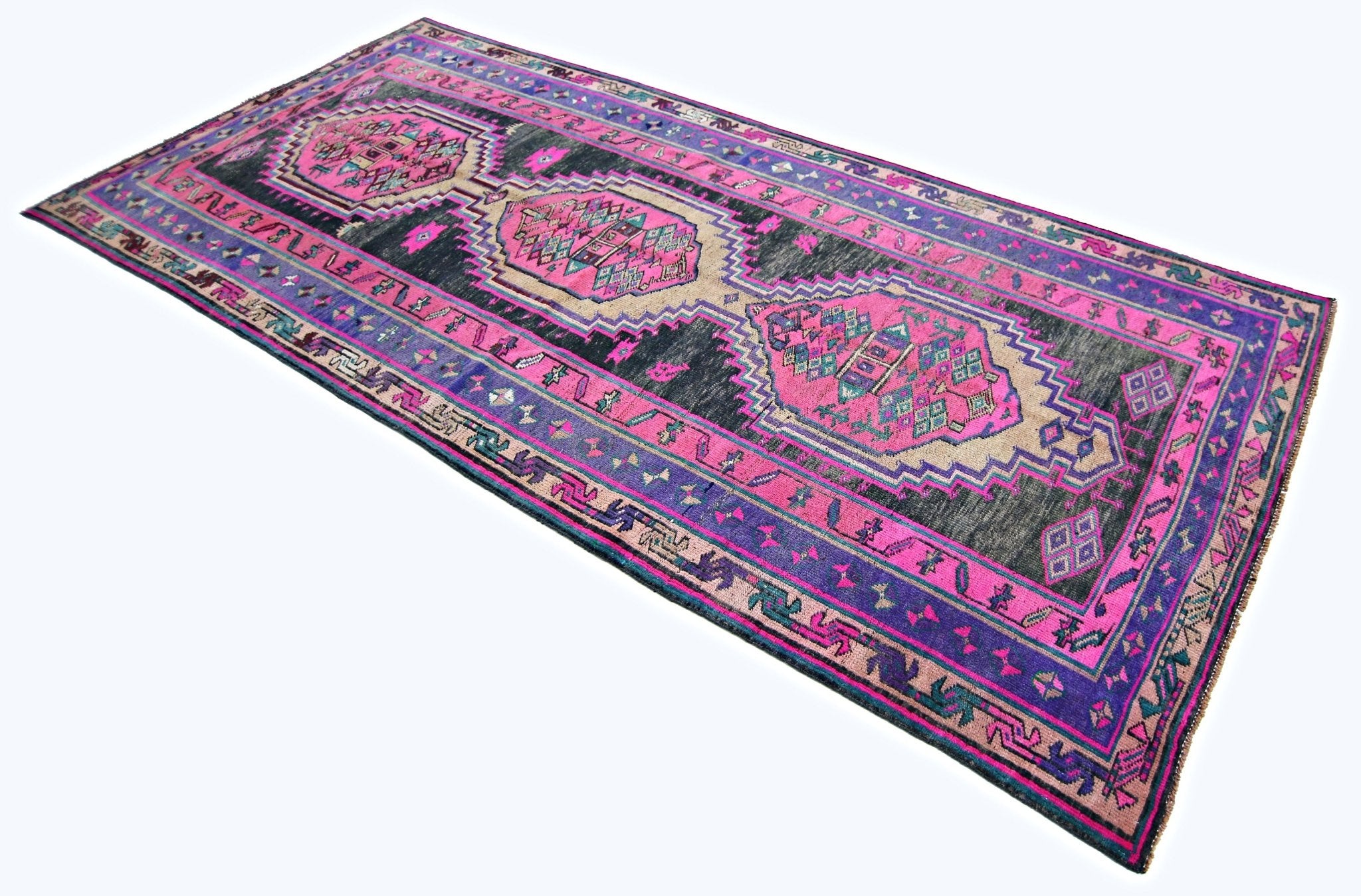 A vintage Persian Lori runner featuring geometric medallions in vibrant pink, purple, and black.