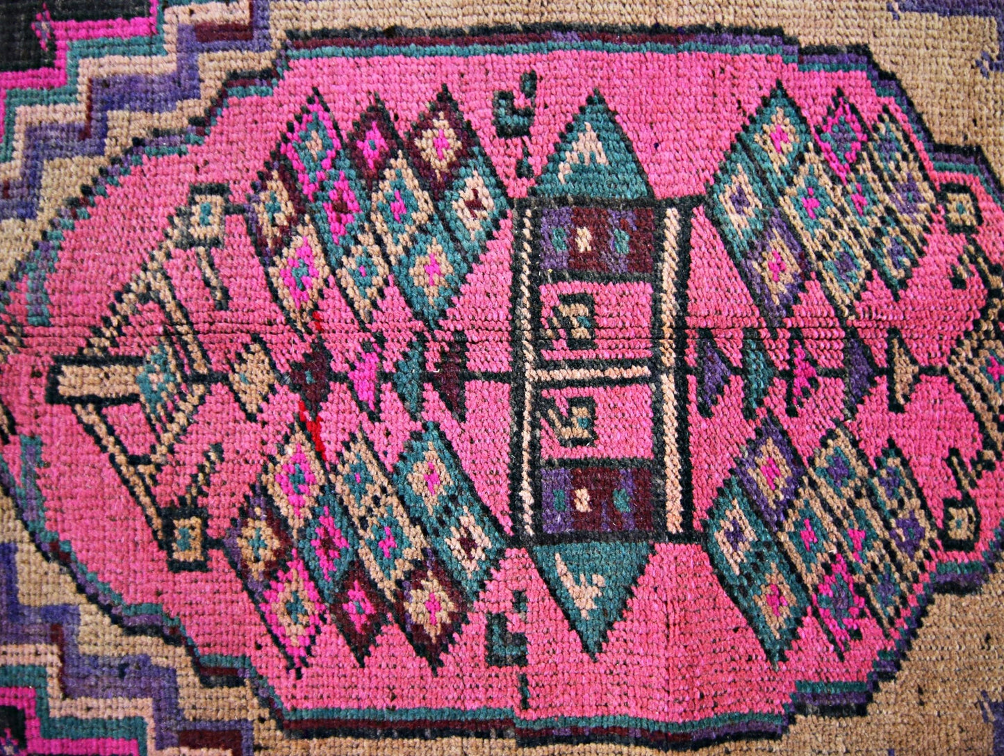 A vintage Persian Lori runner featuring a vibrant pink central medallion with geometric patterns.