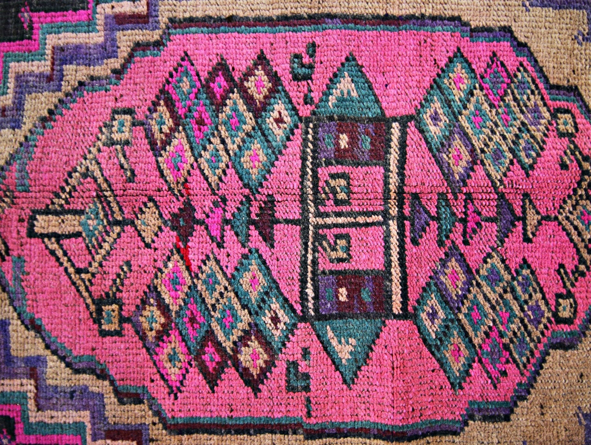 A vintage Persian Lori runner featuring a vibrant pink central medallion with geometric patterns.