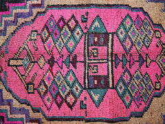 A vintage Persian Lori runner featuring a vibrant pink central medallion with geometric patterns.