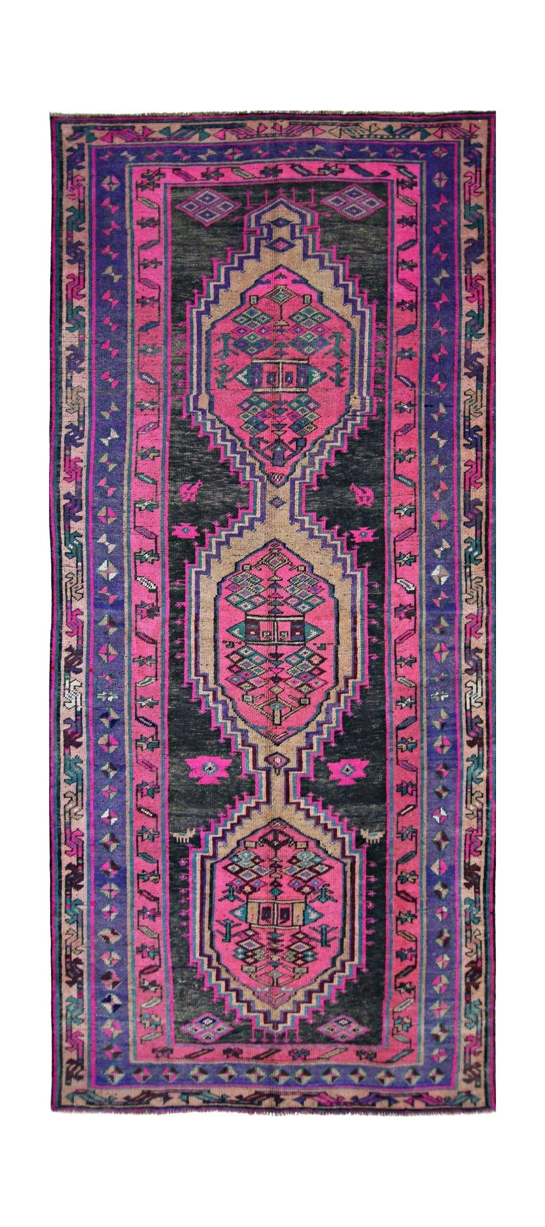 A vintage Persian Lori runner featuring geometric medallions in vibrant pink, purple, and black.