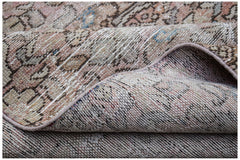 A folded vintage Persian Hamadan runner featuring a faded, intricate pattern in wool.