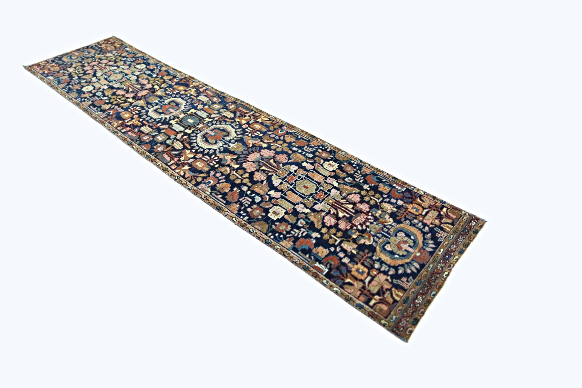 A vintage Persian Malayer runner featuring intricate floral patterns in a dark blue field.