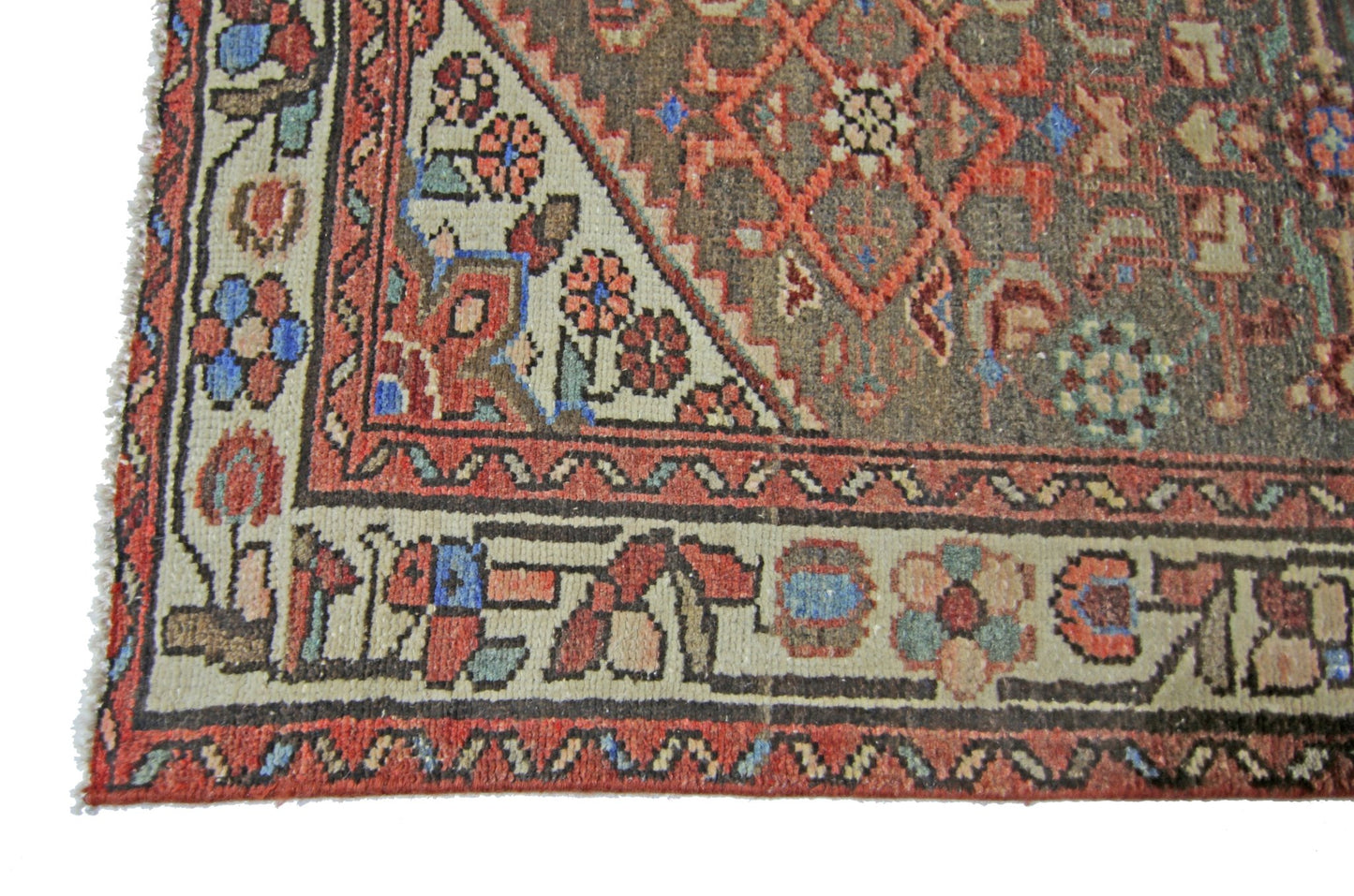A vintage Persian Hamadan runner featuring a geometric floral pattern in red, blue, and brown tones.