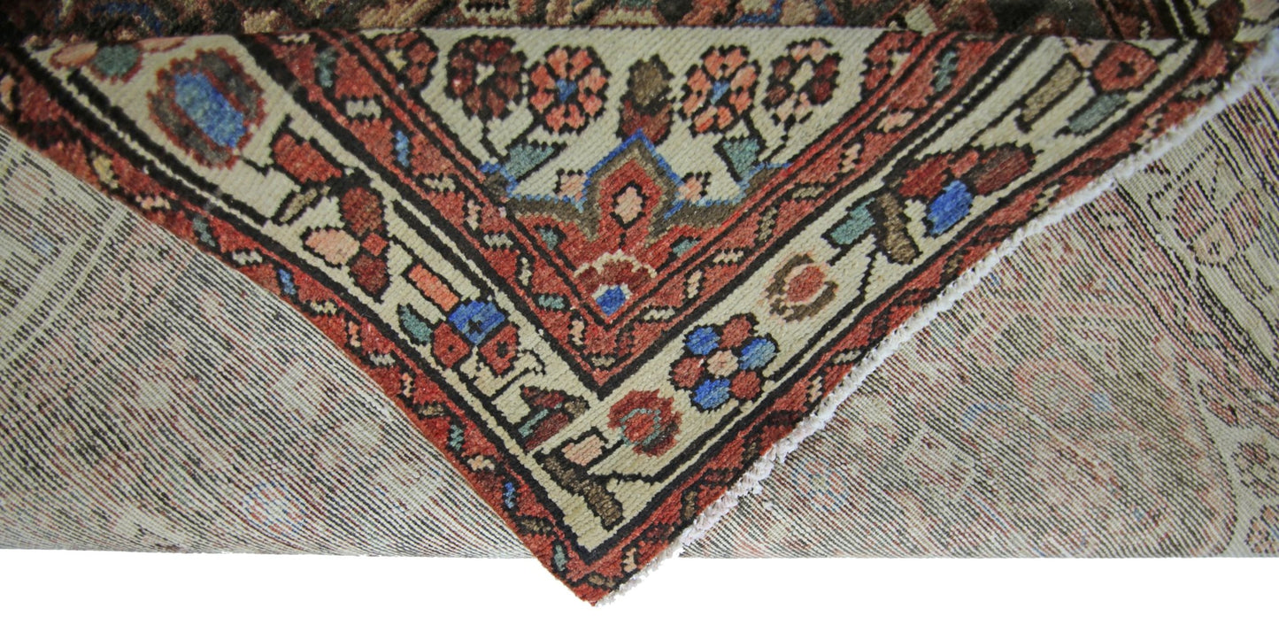 A corner of a vintage Persian Hamadan runner showing its intricate floral pattern and wool weave.