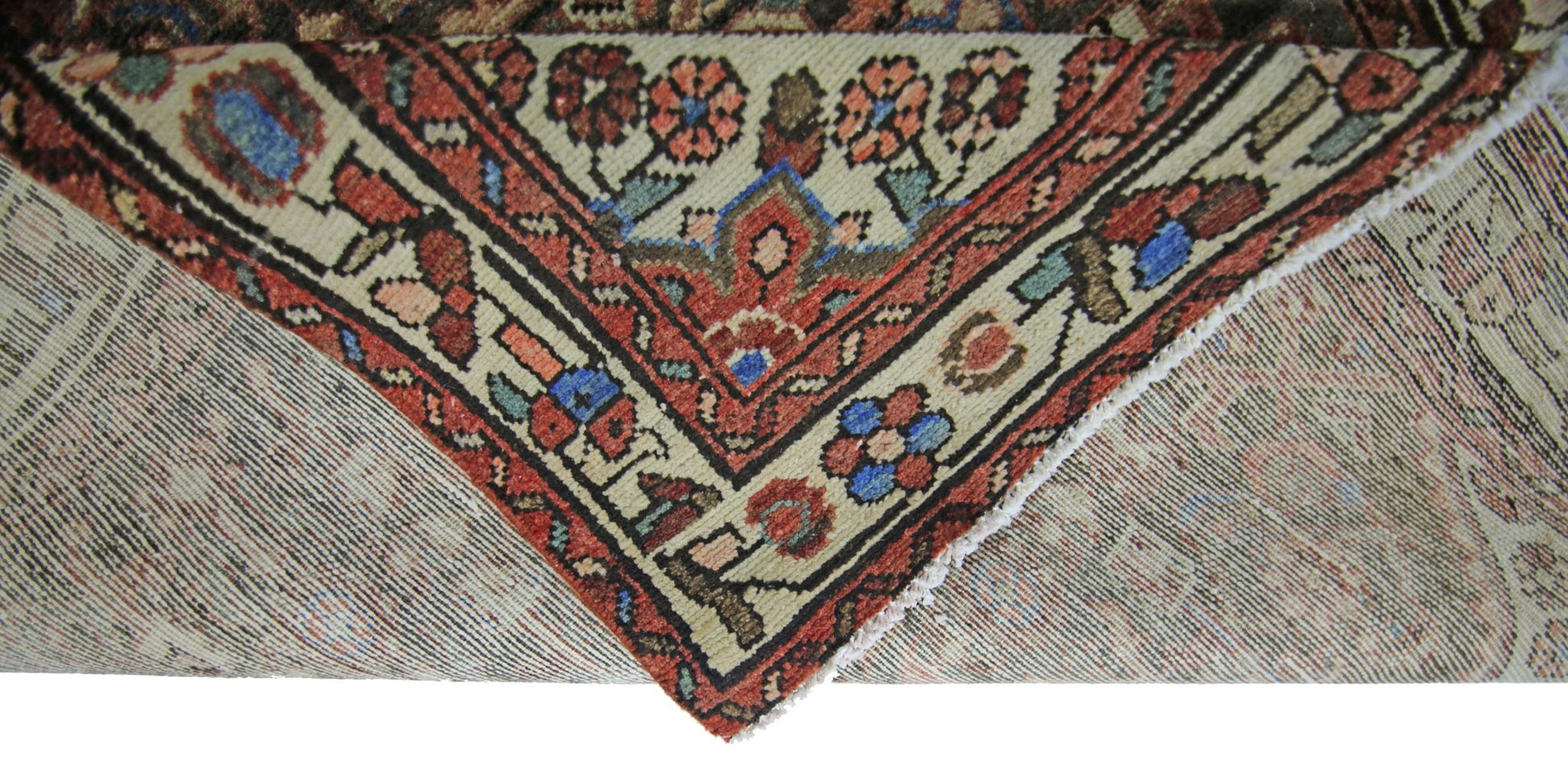 A corner of a vintage Persian Hamadan runner showing its intricate floral pattern and wool weave.